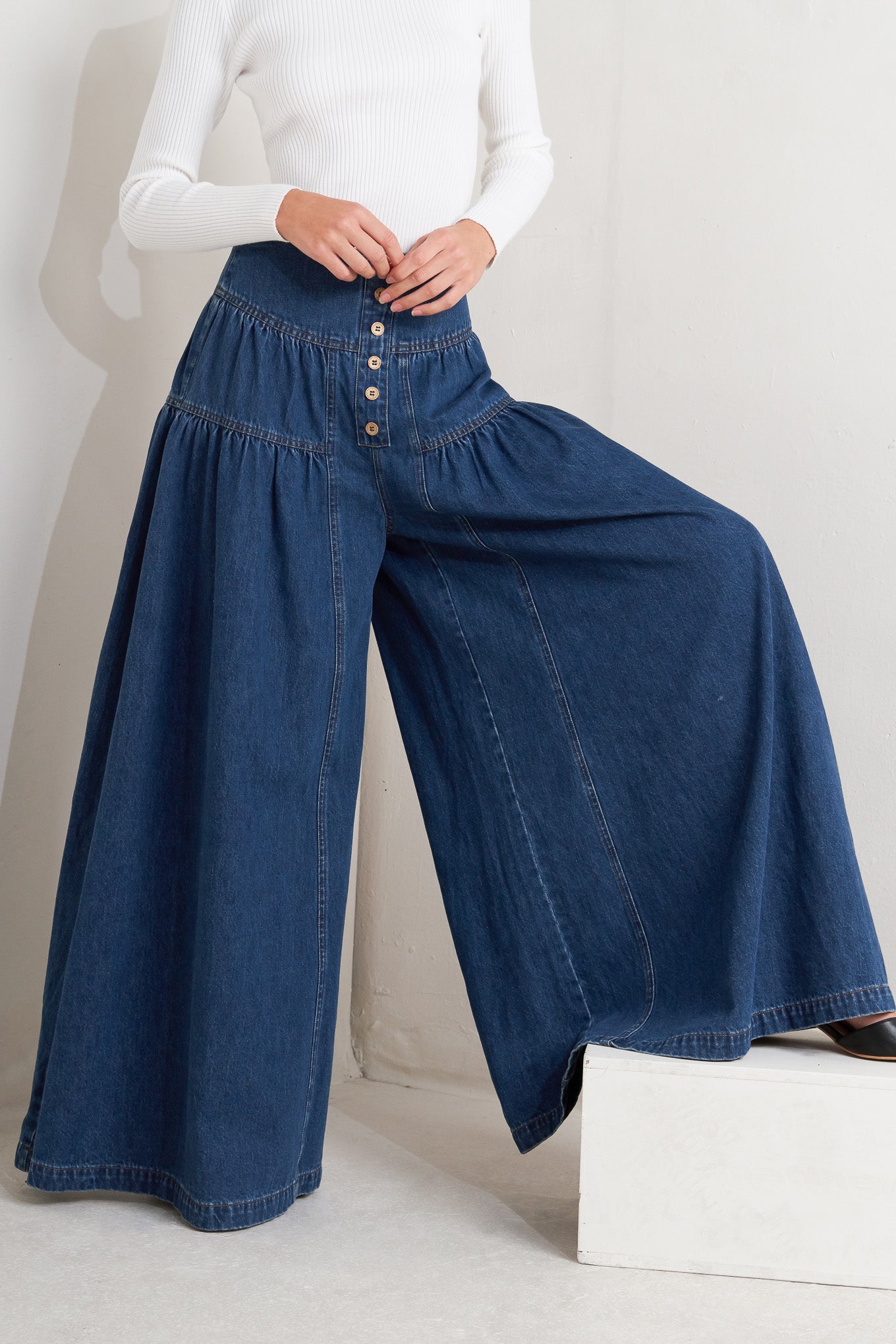 A washed denim pant with front button detail, shirring and back zipper closure