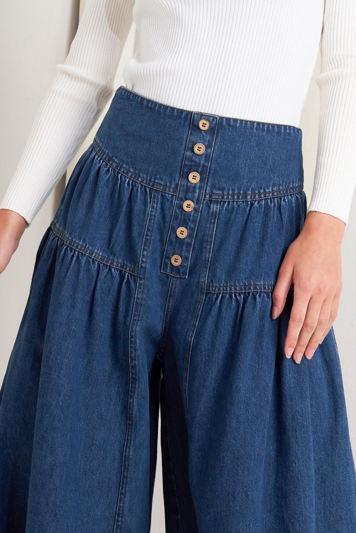 A washed denim pant with front button detail, shirring and back zipper closure