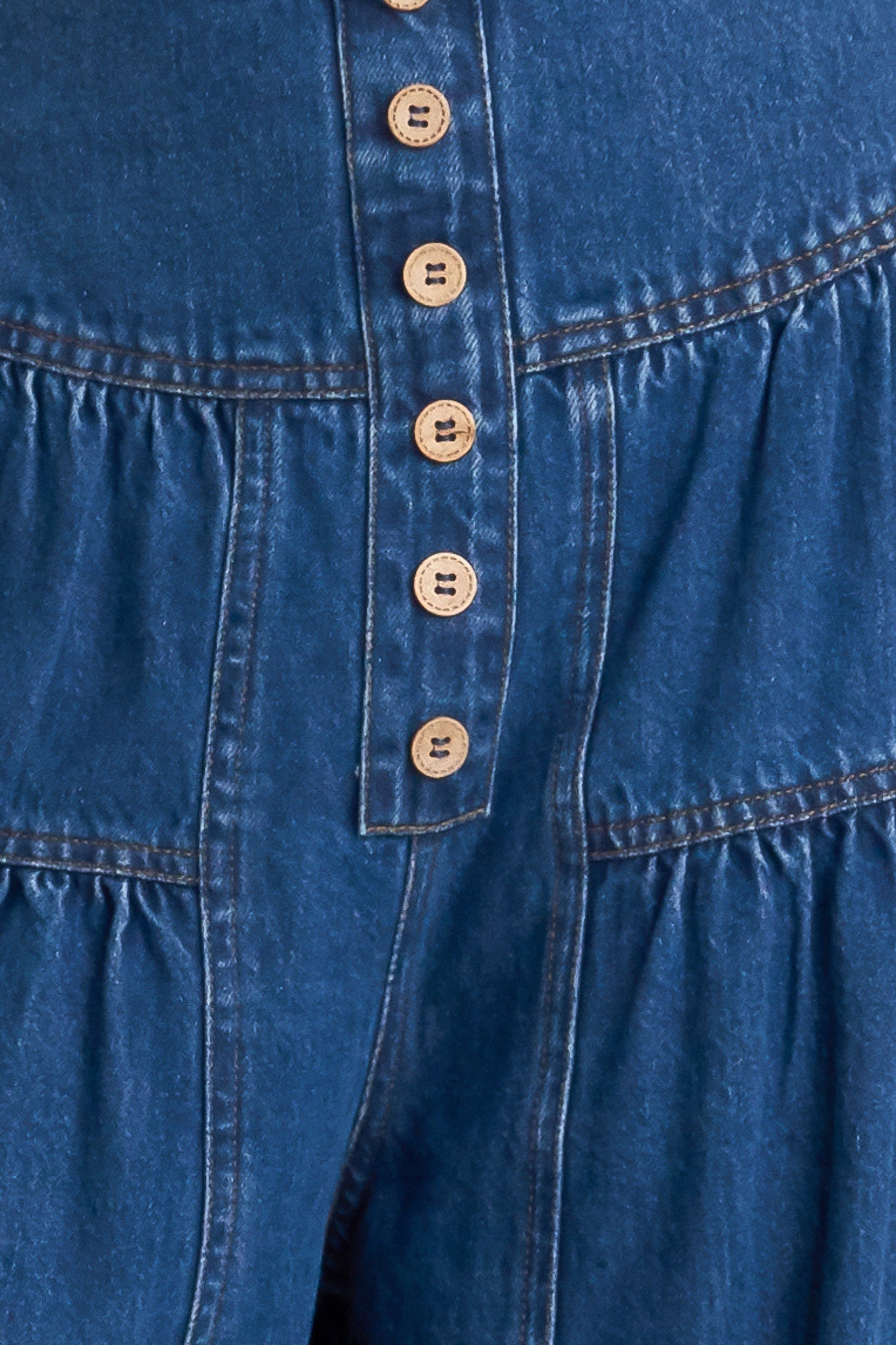 A washed denim pant with front button detail, shirring and back zipper closure