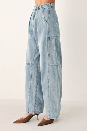 A person wearing light-wash blue denim jeans with a high waist, pleated front, and wide legs | FREEMARKET