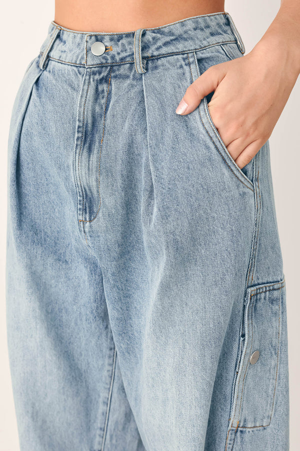 A person wearing light-wash blue denim jeans with a high waist, pleated front, and wide legs | FREEMARKET