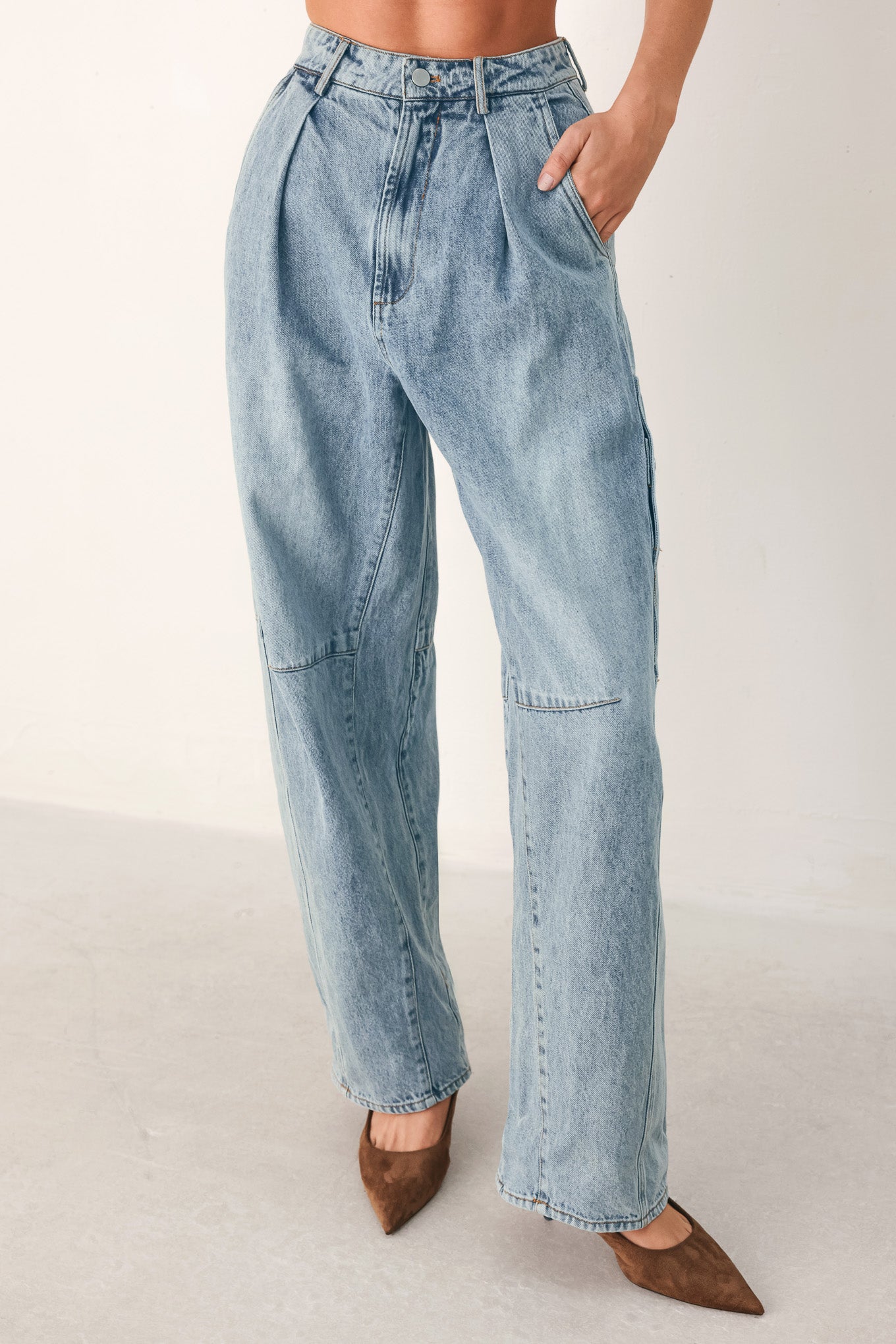 A person wearing light-wash blue denim jeans with a high waist, pleated front, and wide legs | FREEMARKET