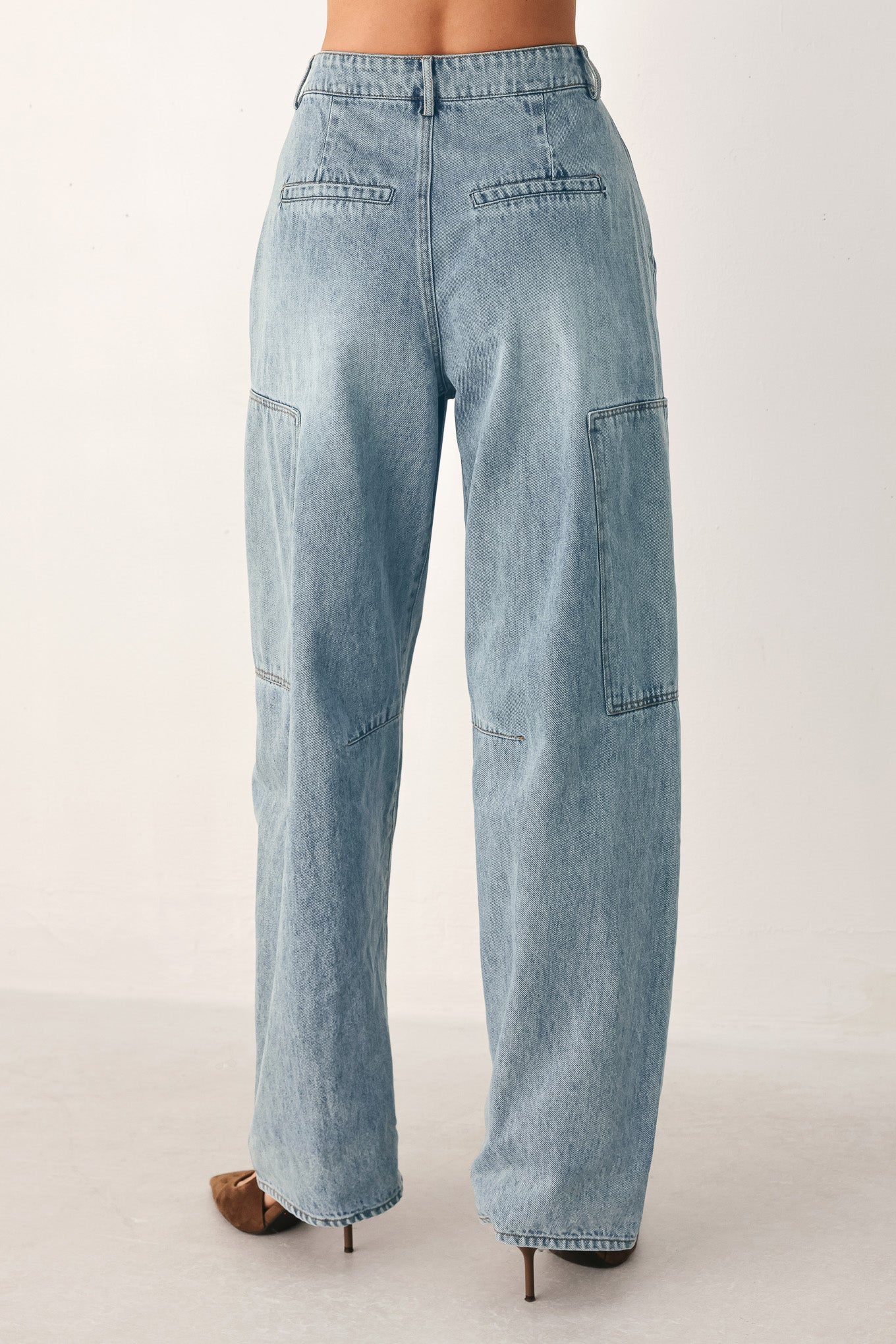 A person wearing light-wash blue denim jeans with a high waist, pleated front, and wide legs | FREEMARKET