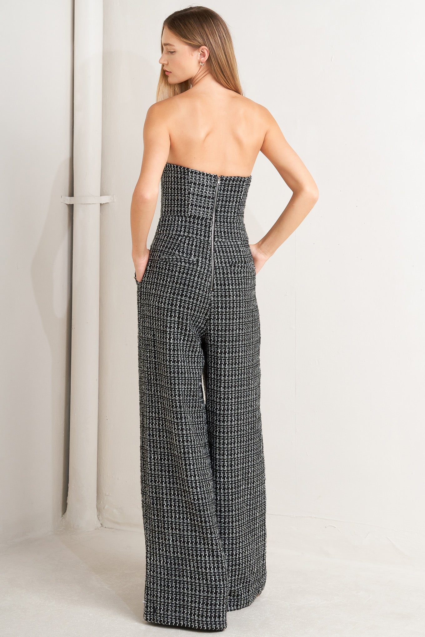 A tweed jumpsuit featuring strapless, side pockets with button detail, wide leg and back zipper closure