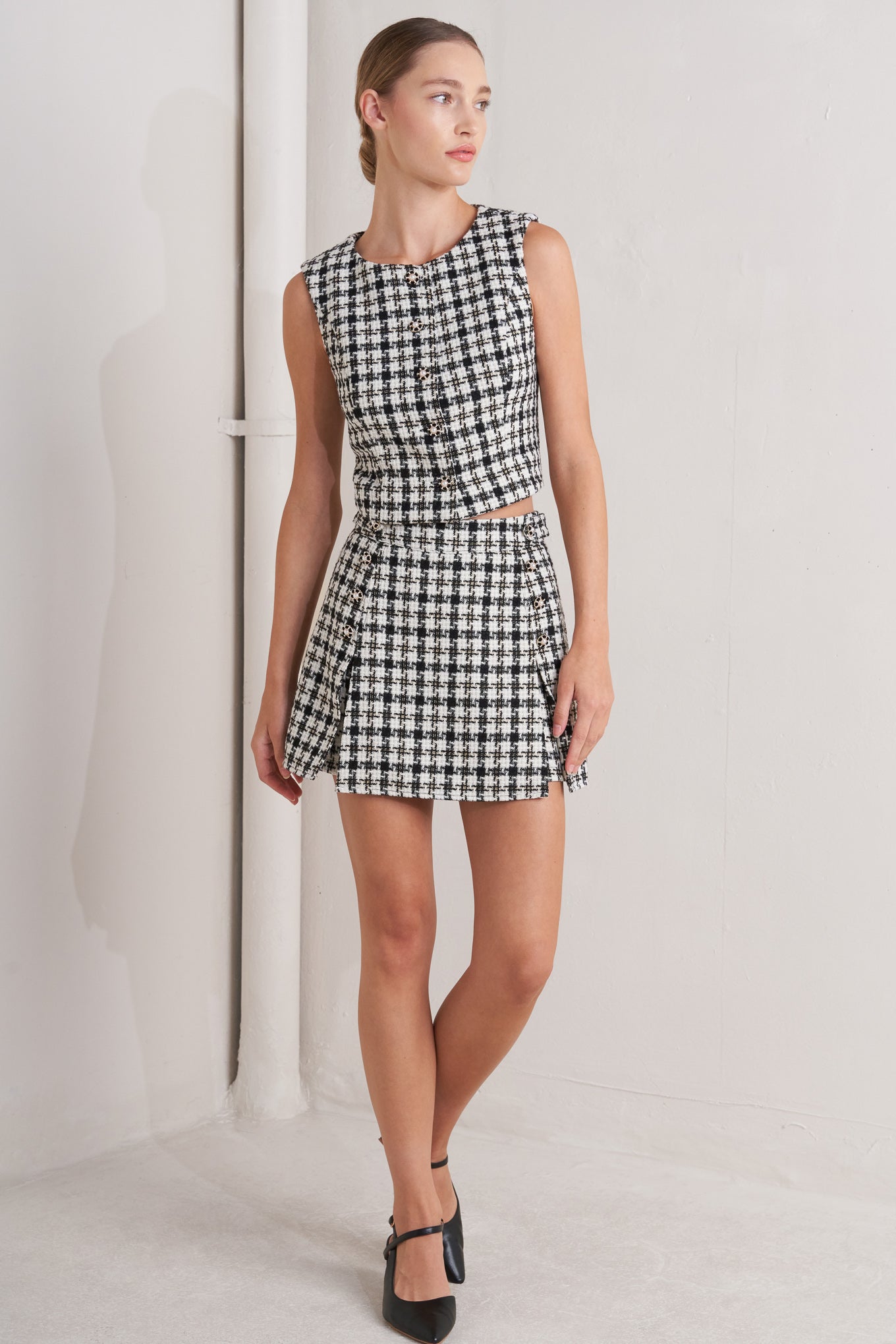 A tweed skort featuring side tag, button detail and back zipper closure.
