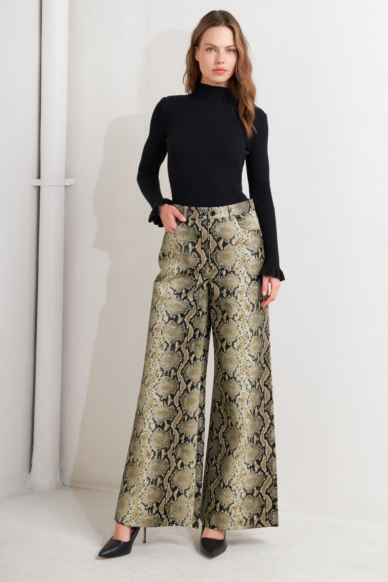 A printed faux leather pant with front closure, side pockets, and wide leg