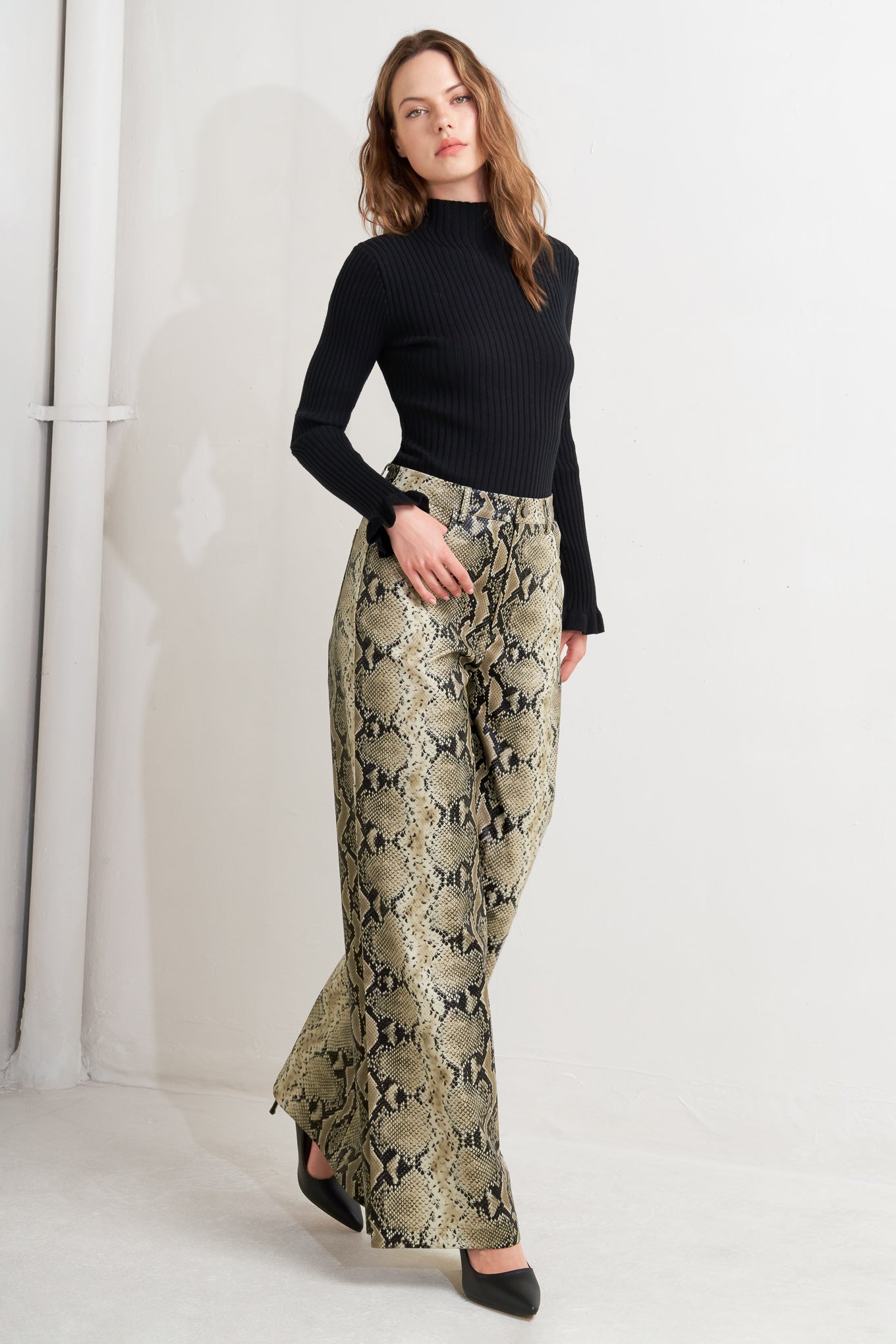 A printed faux leather pant with front closure, side pockets, and wide leg