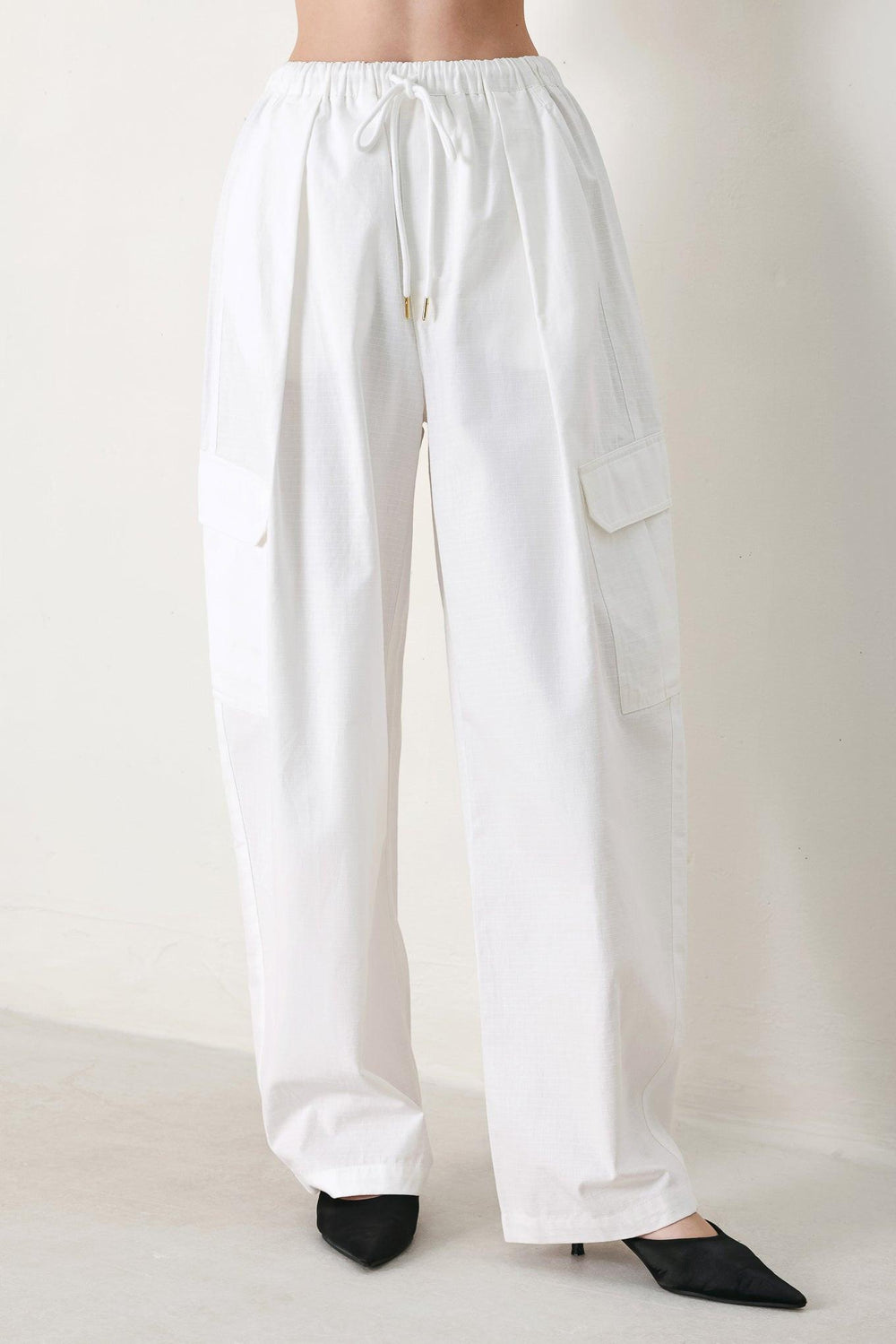 A solid woven balloon pant featuring elastic waist with tie and pockets