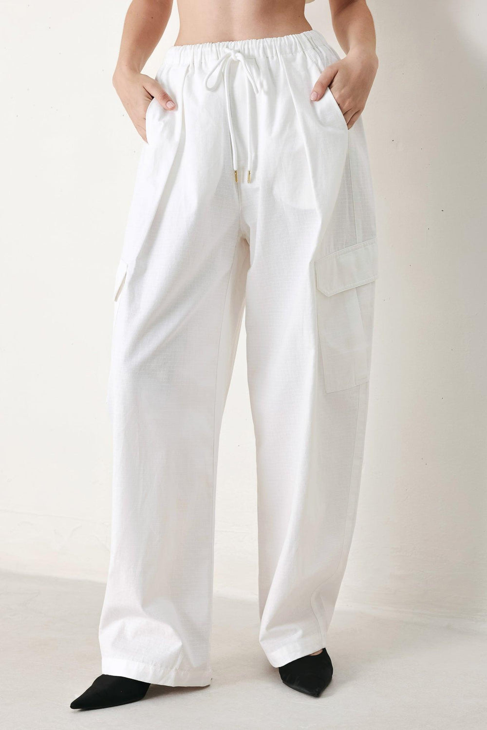 A solid woven balloon pant featuring elastic waist with tie and pockets