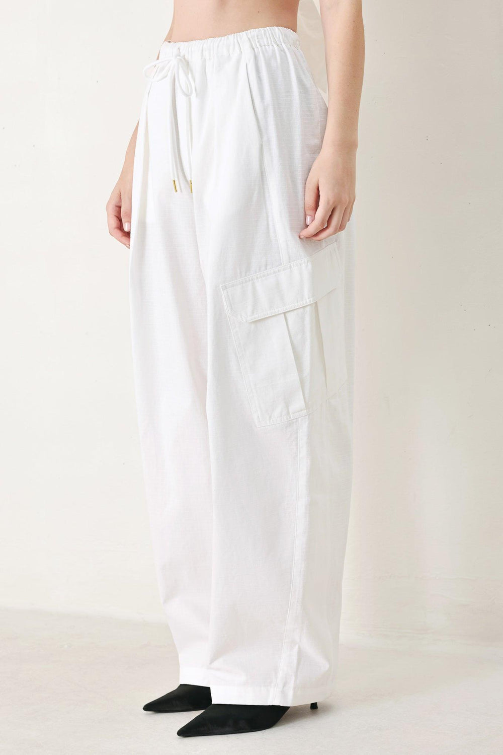 A solid woven balloon pant featuring elastic waist with tie and pockets
