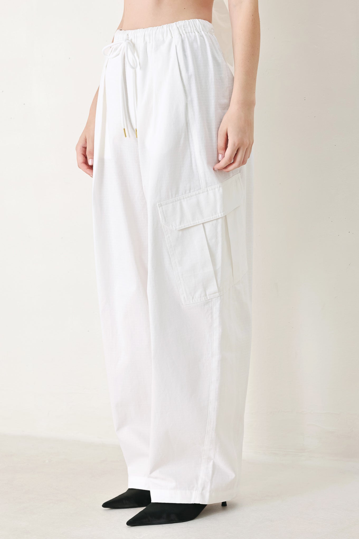 A solid woven balloon pant featuring elastic waist with tie and pockets