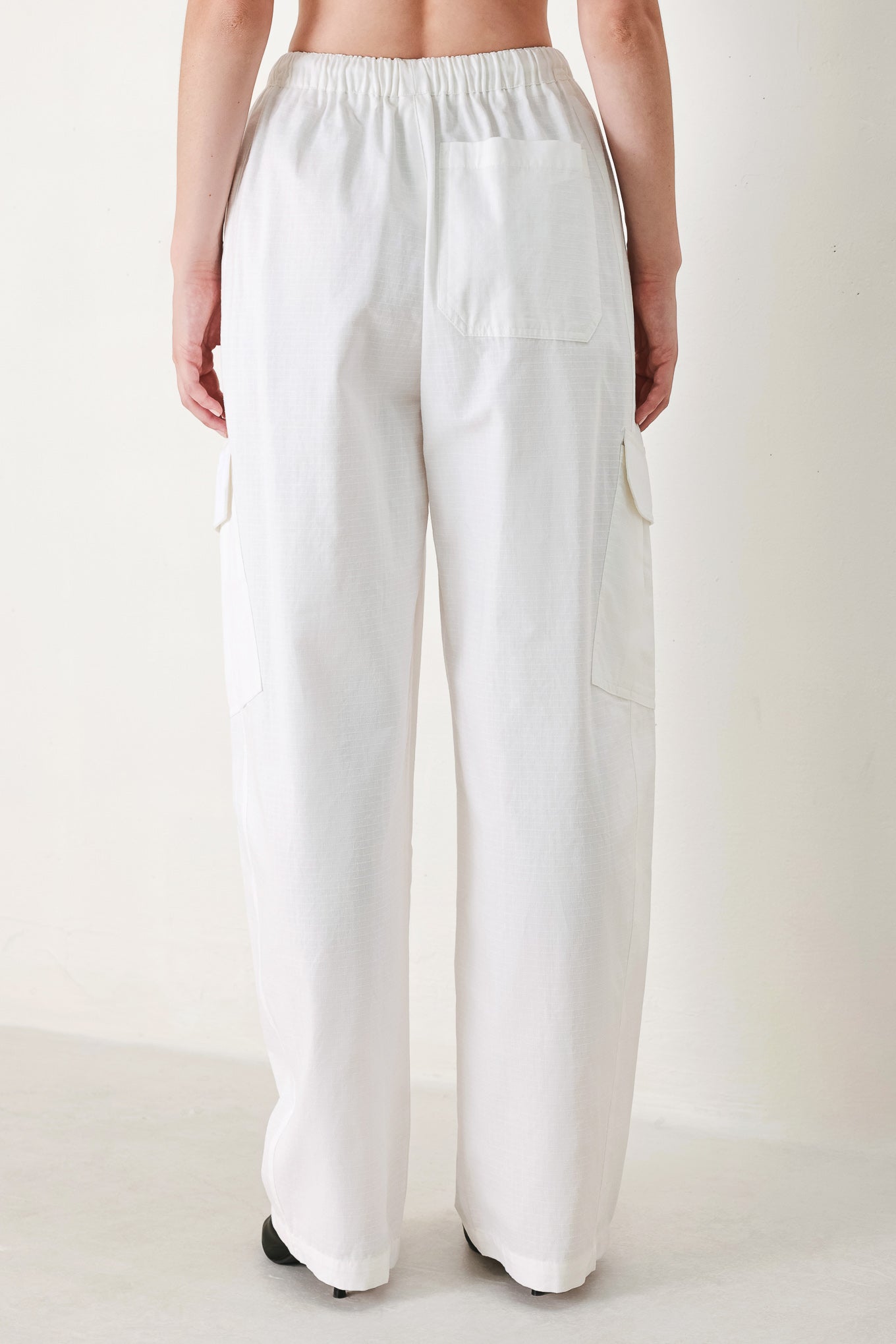 A solid woven balloon pant featuring elastic waist with tie and pockets