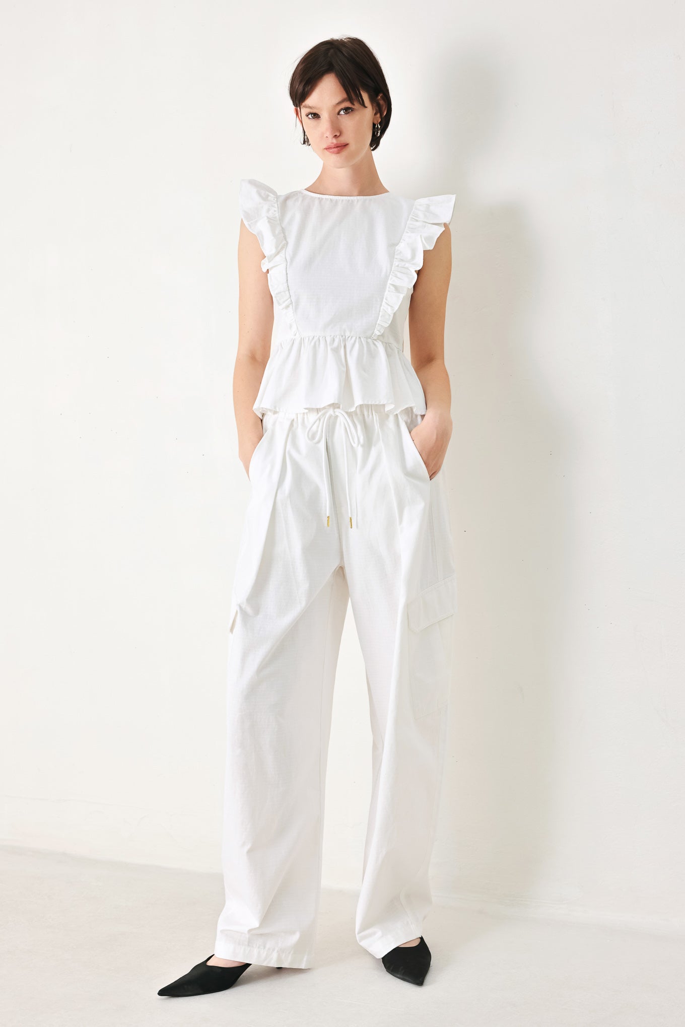 A solid woven balloon pant featuring elastic waist with tie and pockets
