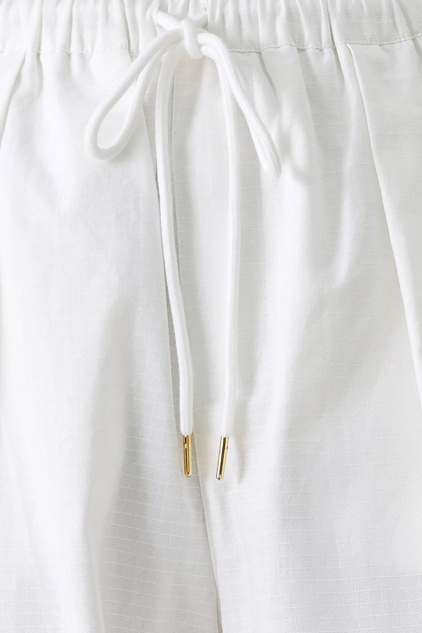 A solid woven balloon pant featuring elastic waist with tie and pockets