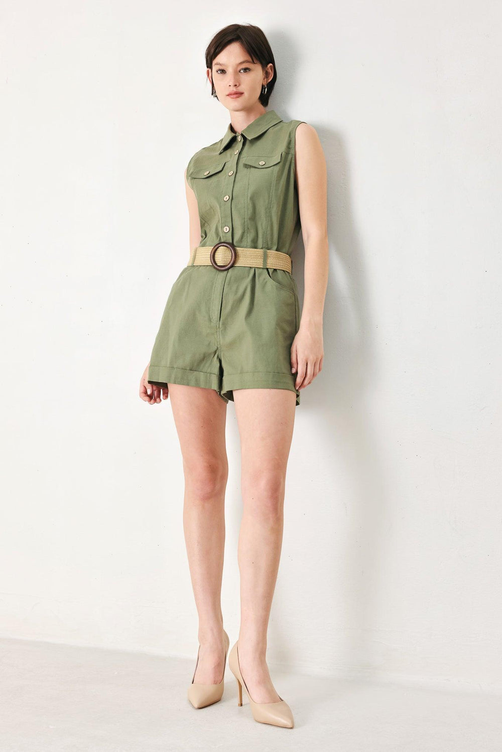 A solid woven romper featuring collar, sleeveless, front button zipper closure, pockets, cuffed hem and contrasting belt