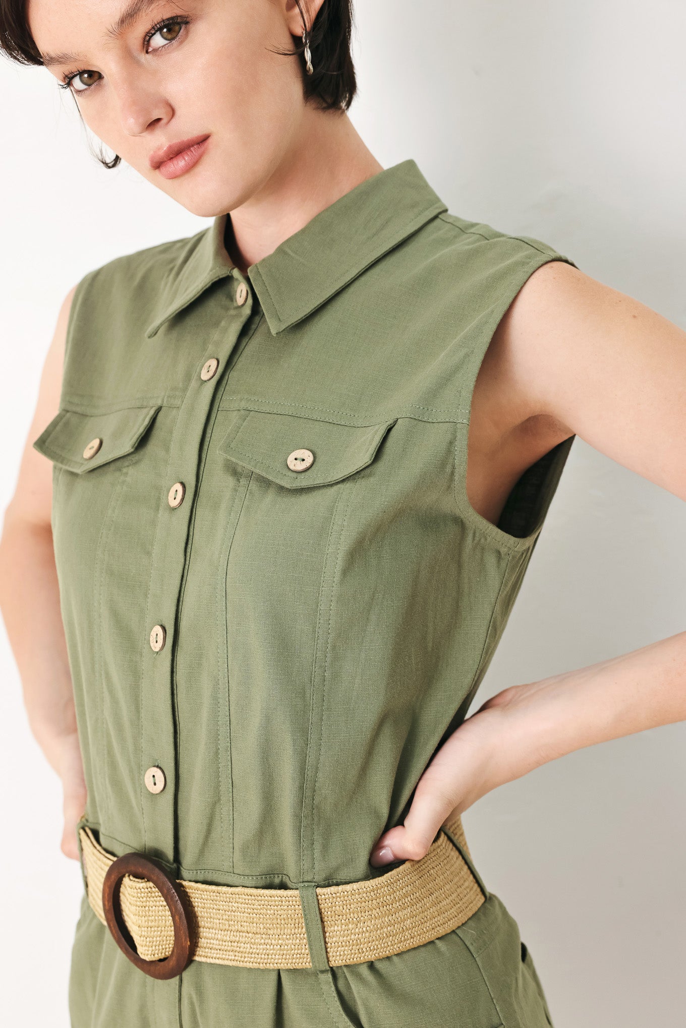 A solid woven romper featuring collar, sleeveless, front button zipper closure, pockets, cuffed hem and contrasting belt