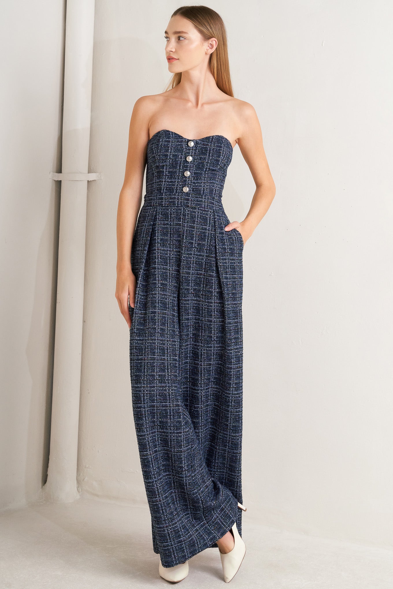 A tweed jumpsuit featuring sweetheart neckline, front button detail, side pockets and back zipper closure