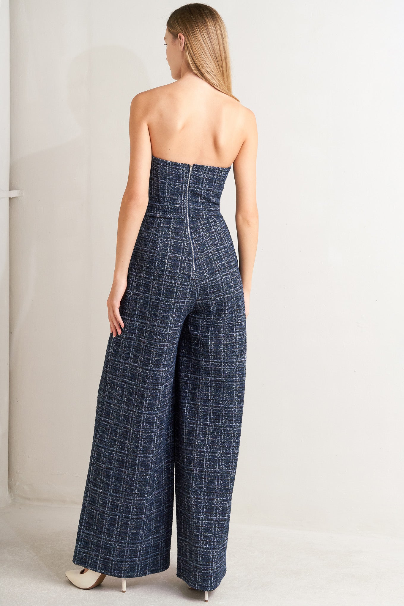 A tweed jumpsuit featuring sweetheart neckline, front button detail, side pockets and back zipper closure