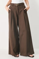 Woman wearing brown wide-leg pants with a pleat on each leg | FREEMARKET
