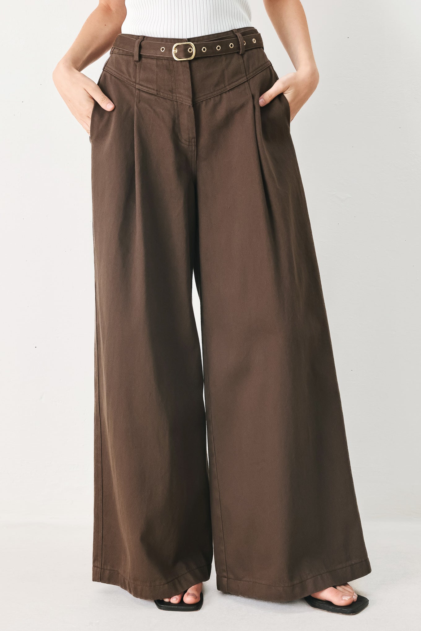 Woman wearing brown wide-leg pants with a pleat on each leg | FREEMARKET