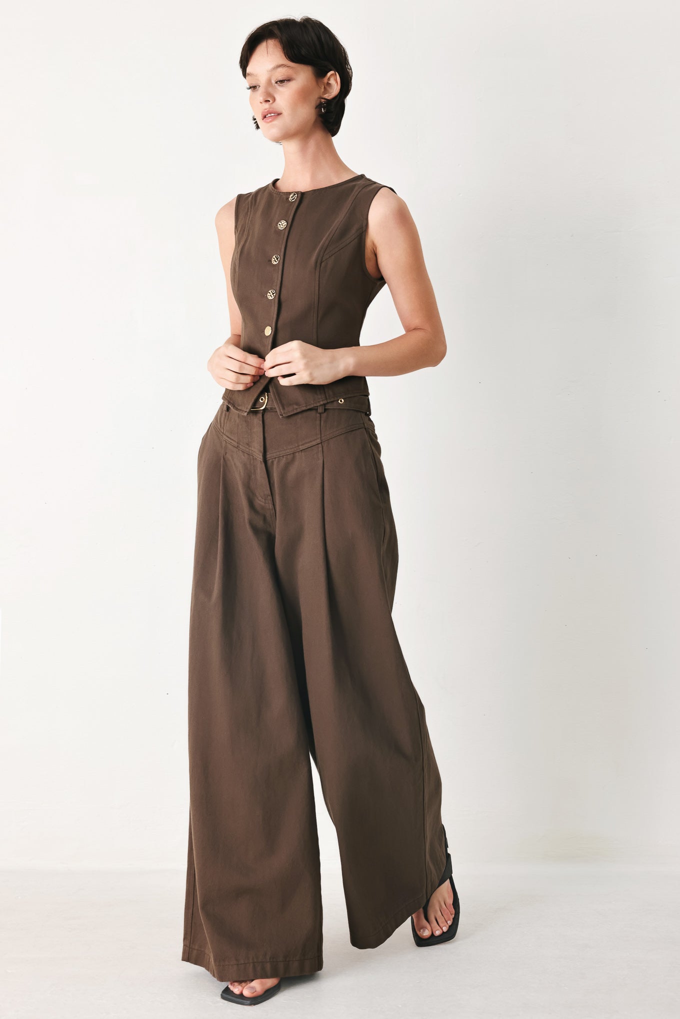 Woman wearing brown wide-leg pants with a pleat on each leg | FREEMARKET