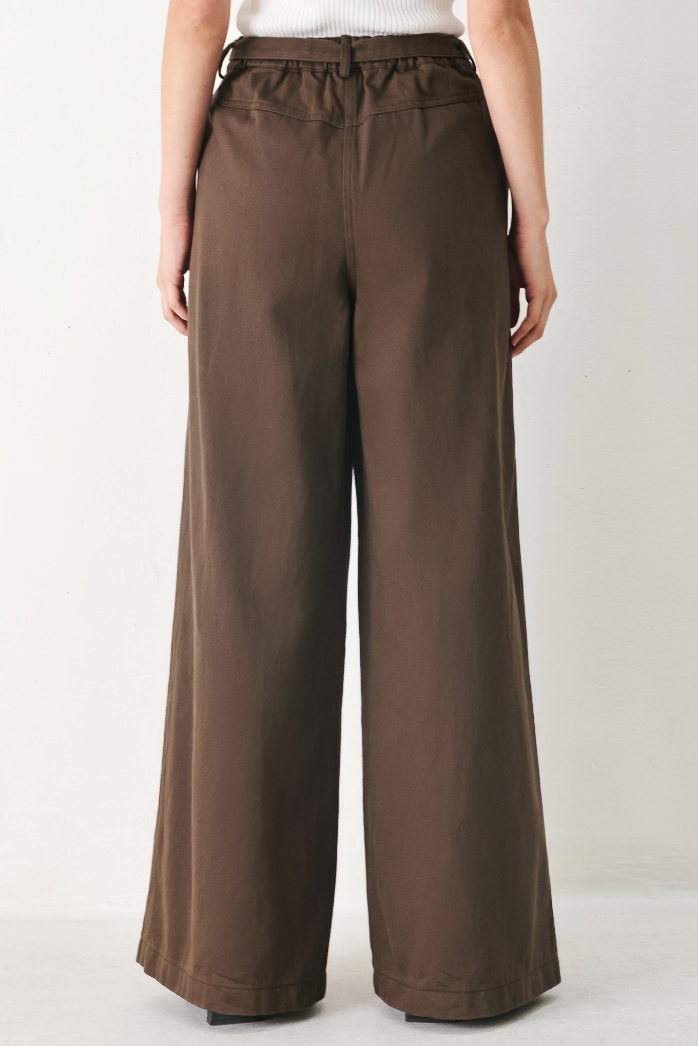 Woman wearing brown wide-leg pants with a pleat on each leg | FREEMARKET