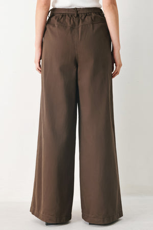 Woman wearing brown wide-leg pants with a pleat on each leg | FREEMARKET