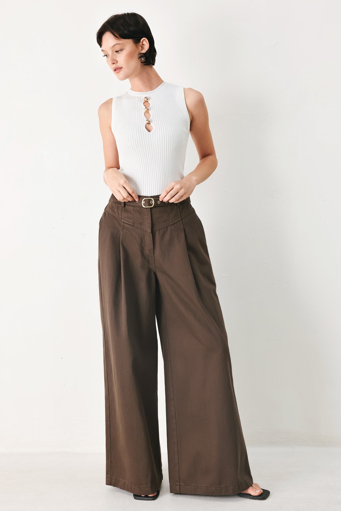 Woman wearing brown wide-leg pants with a pleat on each leg | FREEMARKET