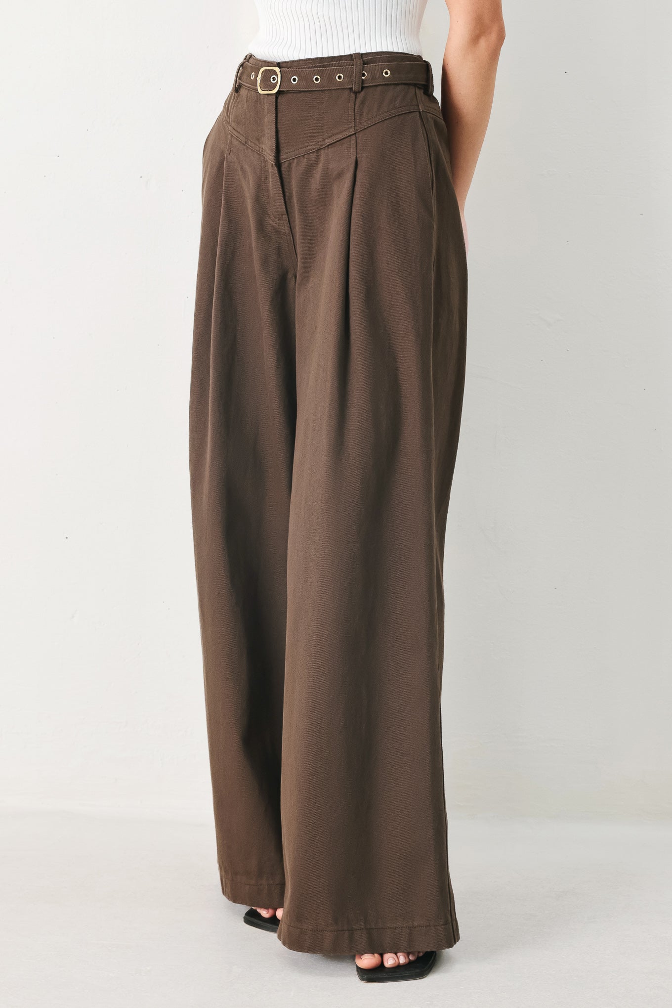 Woman wearing brown wide-leg pants with a pleat on each leg | FREEMARKET
