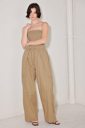 
A solid woven jumpsuit featuring straight neckline with ruffle edge, straps, smocked bodice, elastic waist with tie, pockets and wide leg

Details:

Self : 95% Cotton 5% Spandex

Size &amp; Fit

- Model is 5`8" And Wearing Size Small
- Measurements Taken From Size Small
- Approx. Length: 59"