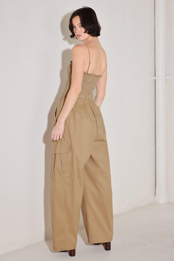 
A solid woven jumpsuit featuring straight neckline with ruffle edge, straps, smocked bodice, elastic waist with tie, pockets and wide leg

Details:

Self : 95% Cotton 5% Spandex

Size &amp; Fit

- Model is 5`8" And Wearing Size Small
- Measurements Taken From Size Small
- Approx. Length: 59"