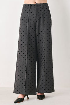 Woman wearing a pair of high waisted charcoal trousers with black polka dots | FREEMARKET