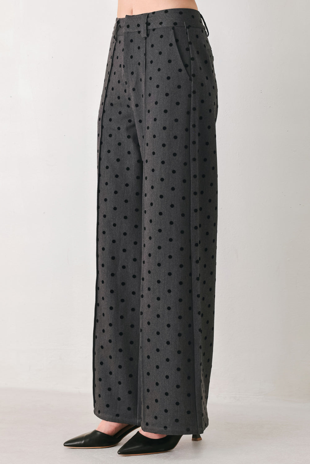 Woman wearing a pair of high waisted charcoal trousers with black polka dots | FREEMARKET