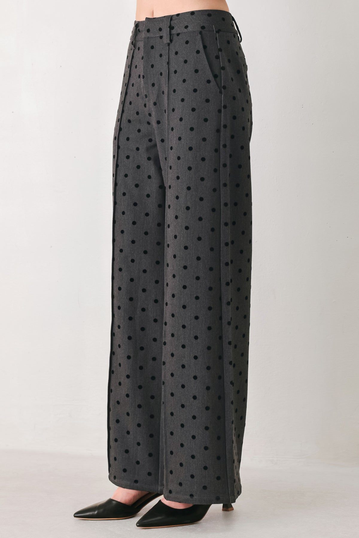 Woman wearing a pair of high waisted charcoal trousers with black polka dots | FREEMARKET