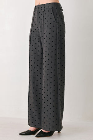 Woman wearing a pair of high waisted charcoal trousers with black polka dots | FREEMARKET