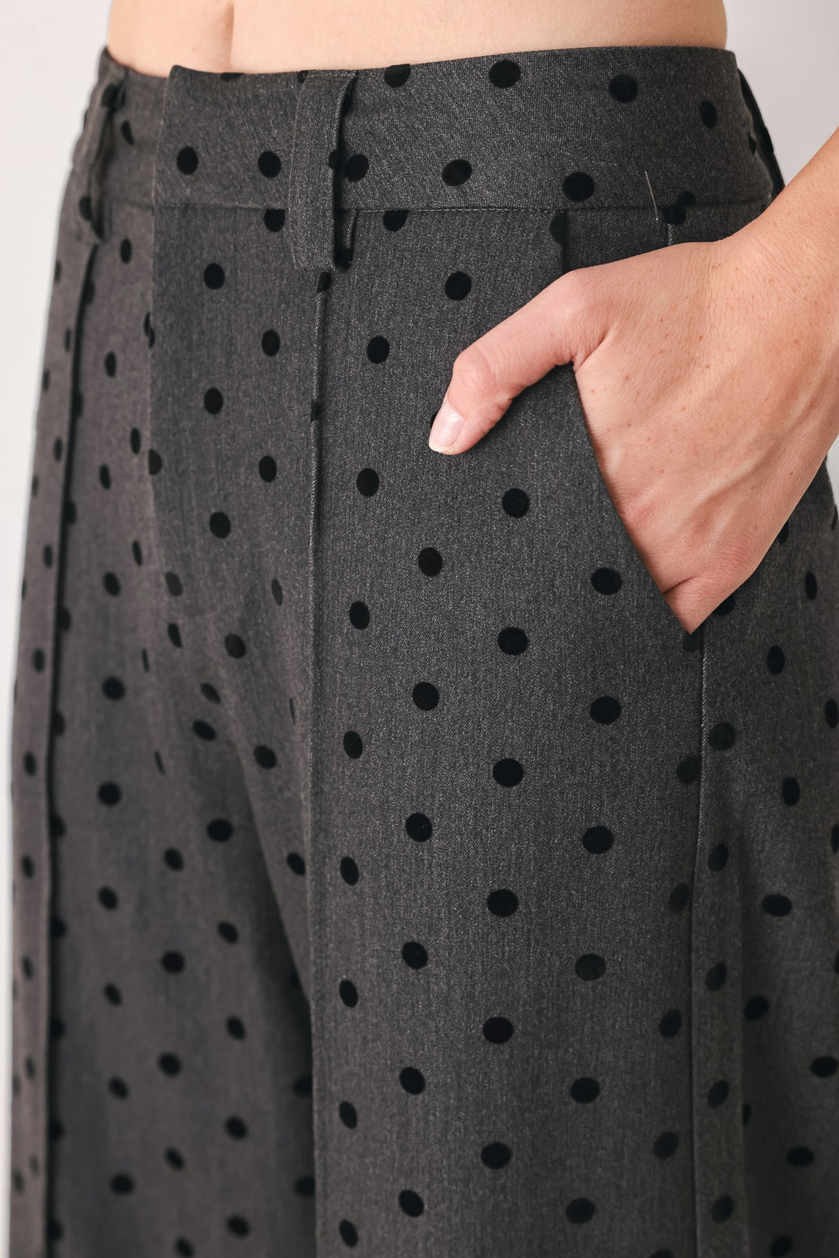 Woman wearing a pair of high waisted charcoal trousers with black polka dots | FREEMARKET