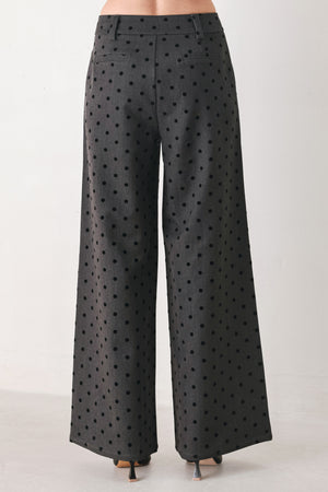 Woman wearing a pair of high waisted charcoal trousers with black polka dots | FREEMARKET