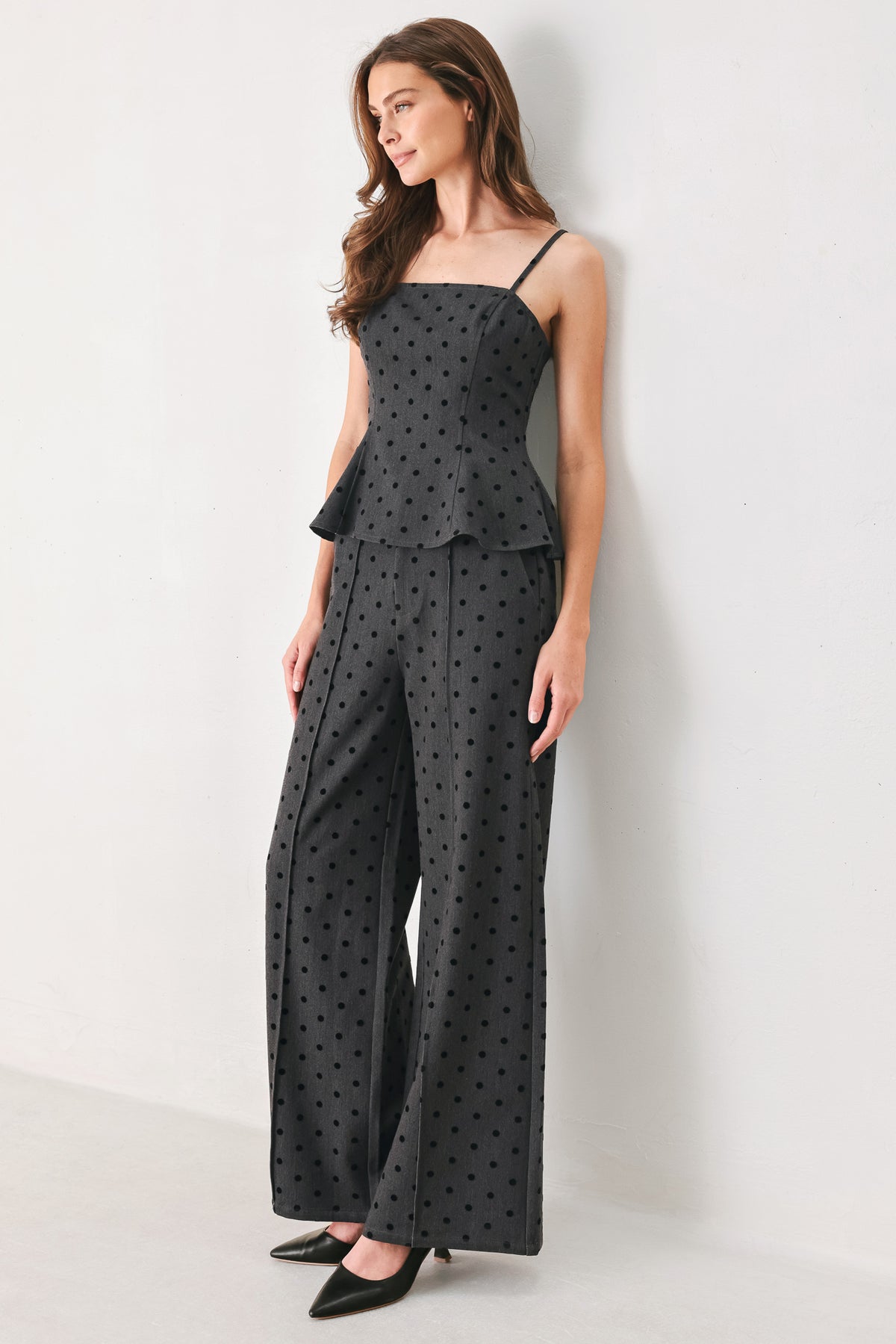 Woman wearing a pair of high waisted charcoal trousers with black polka dots | FREEMARKET