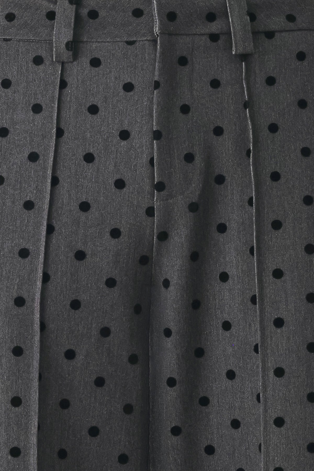 Woman wearing a pair of high waisted charcoal trousers with black polka dots | FREEMARKET