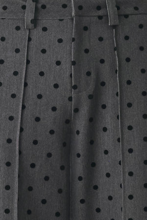 Woman wearing a pair of high waisted charcoal trousers with black polka dots | FREEMARKET