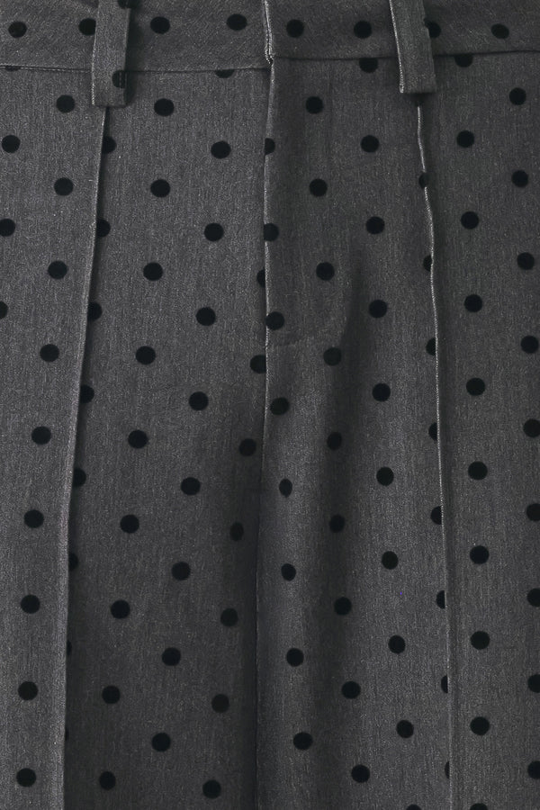 Woman wearing a pair of high waisted charcoal trousers with black polka dots | FREEMARKET