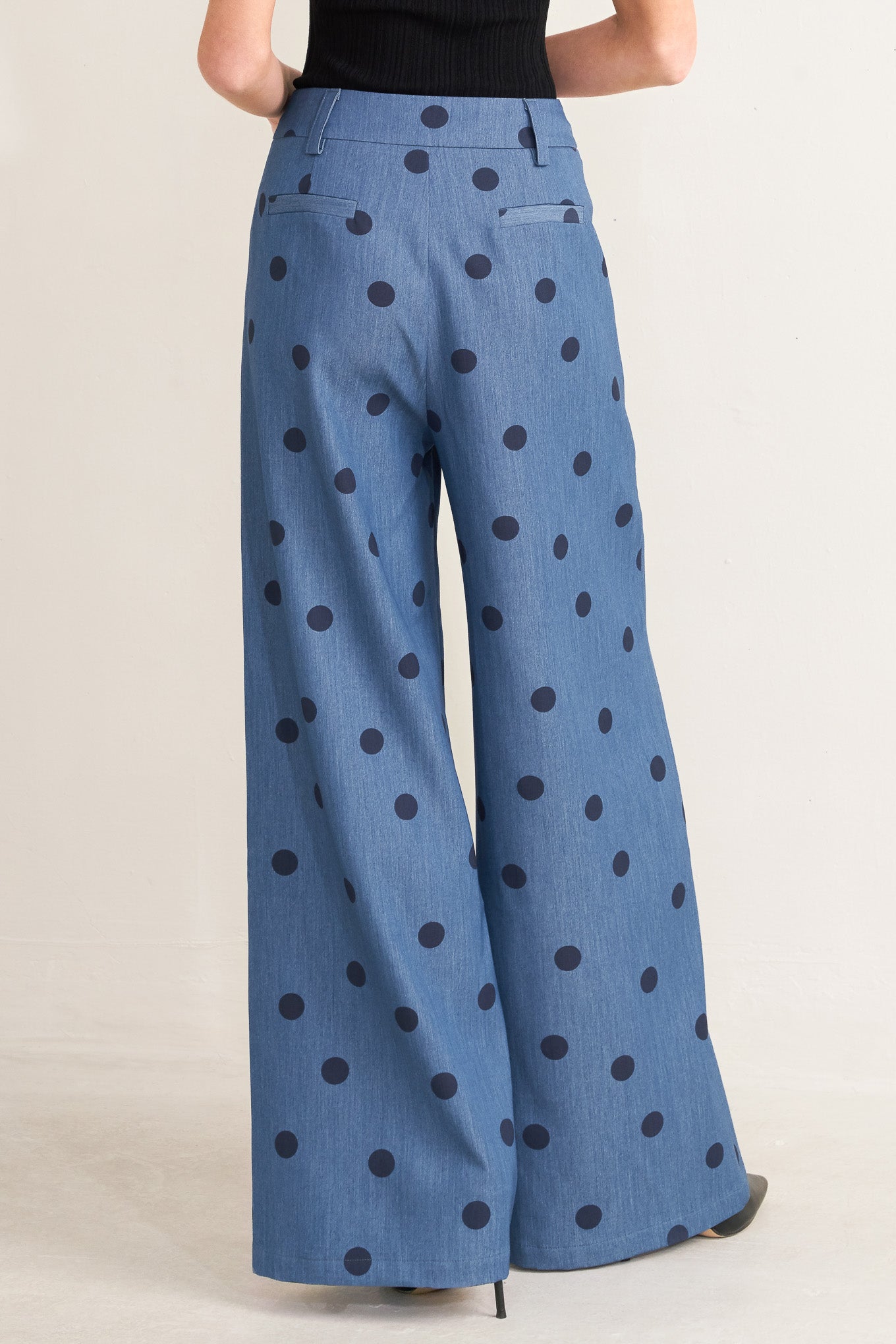 Blue pants with black polka dots worn by a person on a plain background