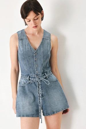 A washed denim romper featuring V neckline, sleeveless, front button/zipper closure, pockets and skinny waist tie
