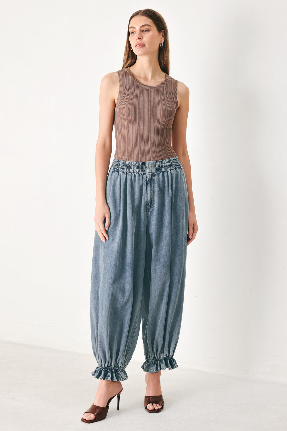 Woman wearing light blue denim genie pants with elastic waist, front closure and side pockets | FREEMARKET | Flying Tomato