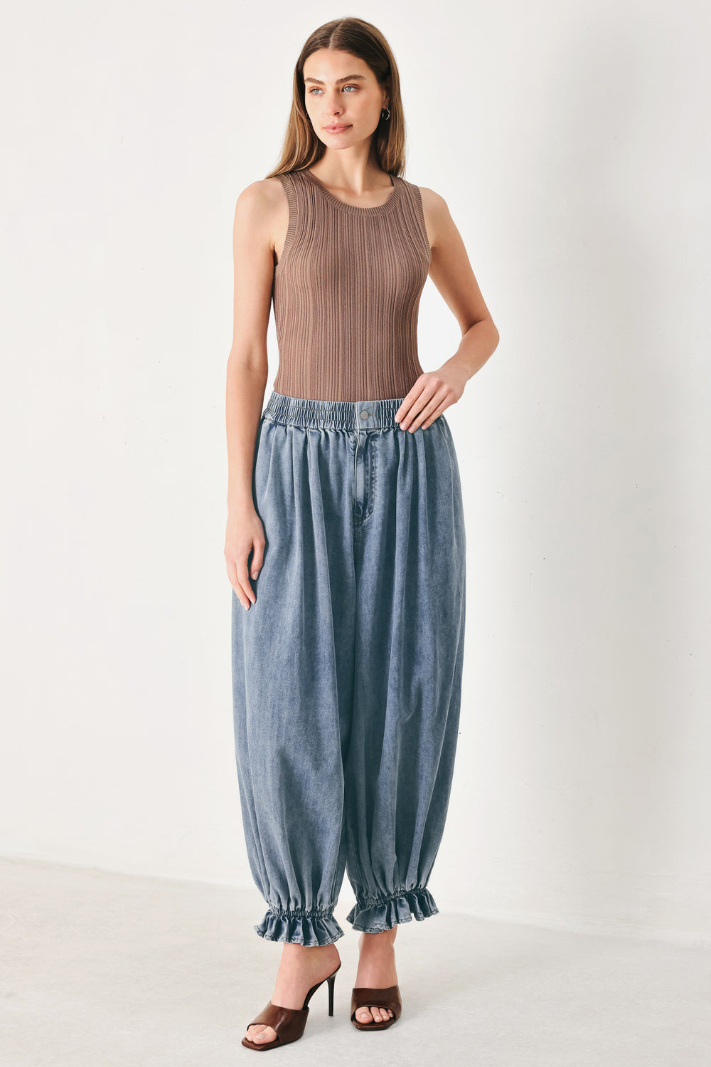 Woman wearing light blue denim genie pants with elastic waist, front closure and side pockets | FREEMARKET | Flying Tomato