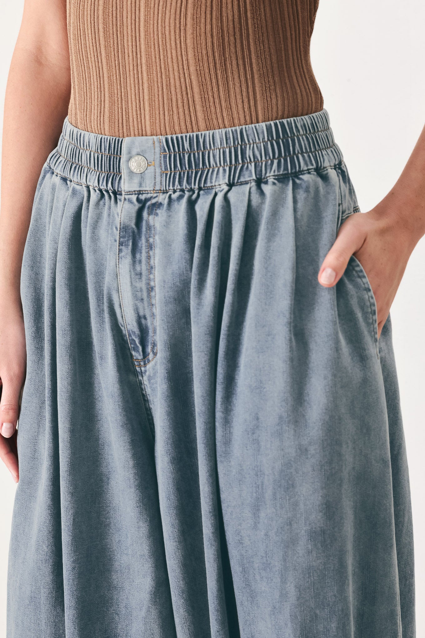 Woman wearing light blue denim genie pants with elastic waist, front closure and side pockets | FREEMARKET | Flying Tomato
