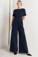
A solid woven jumpsuit featuring wide neckline, short sleeve, self belt, wide leg, V back and zipper closure

Self : 95% Polyester 5% Spandex

Size &amp; Fit

- Model is 5`8" And Wearing Size Small
- Measurements Taken From Size Small
- Approx. Length: 60"