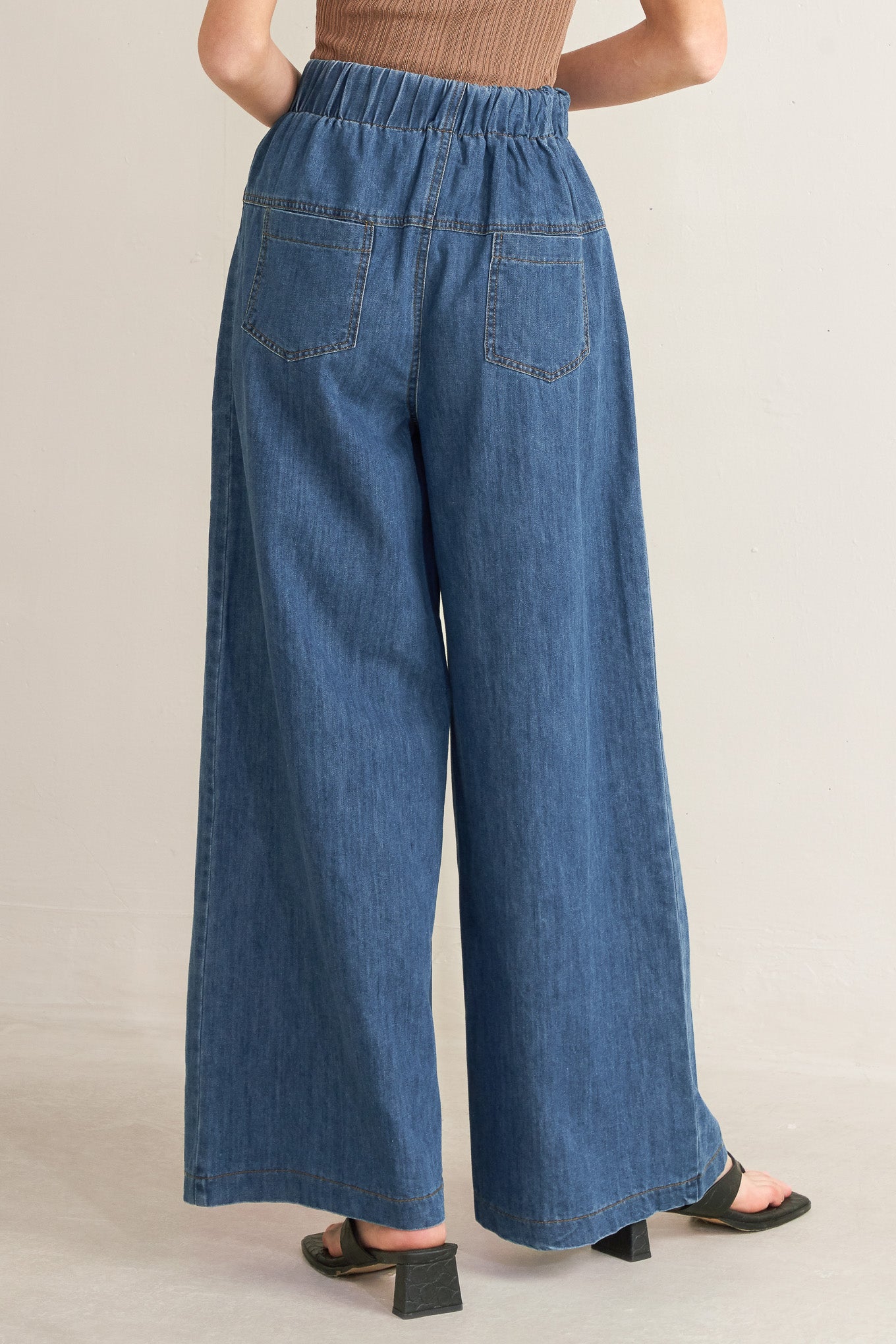 Person wearing blue denim wide-leg pants on a plain background