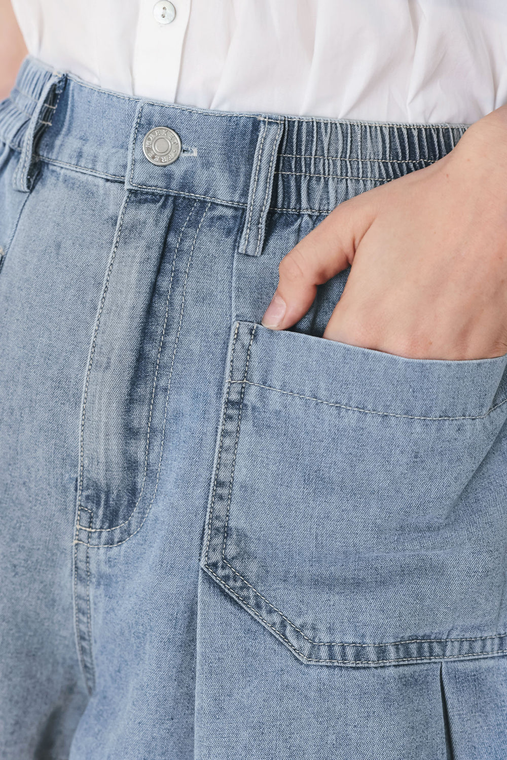 Woman wearing washed light denim short featuring elastic waist, front closure, front pockets and pleats with wide leg | FREEMARKET