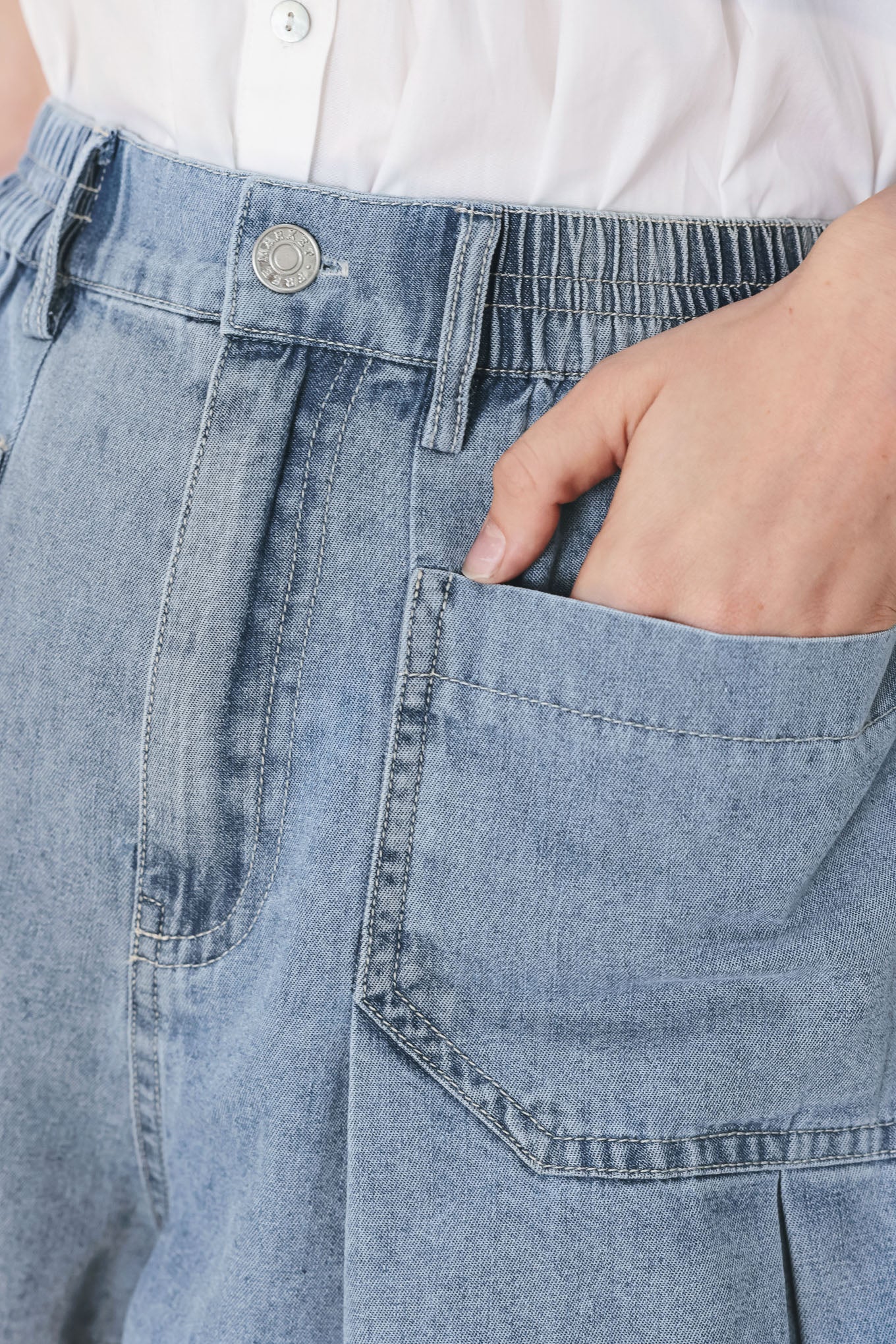 Woman wearing washed light denim short featuring elastic waist, front closure, front pockets and pleats with wide leg | FREEMARKET